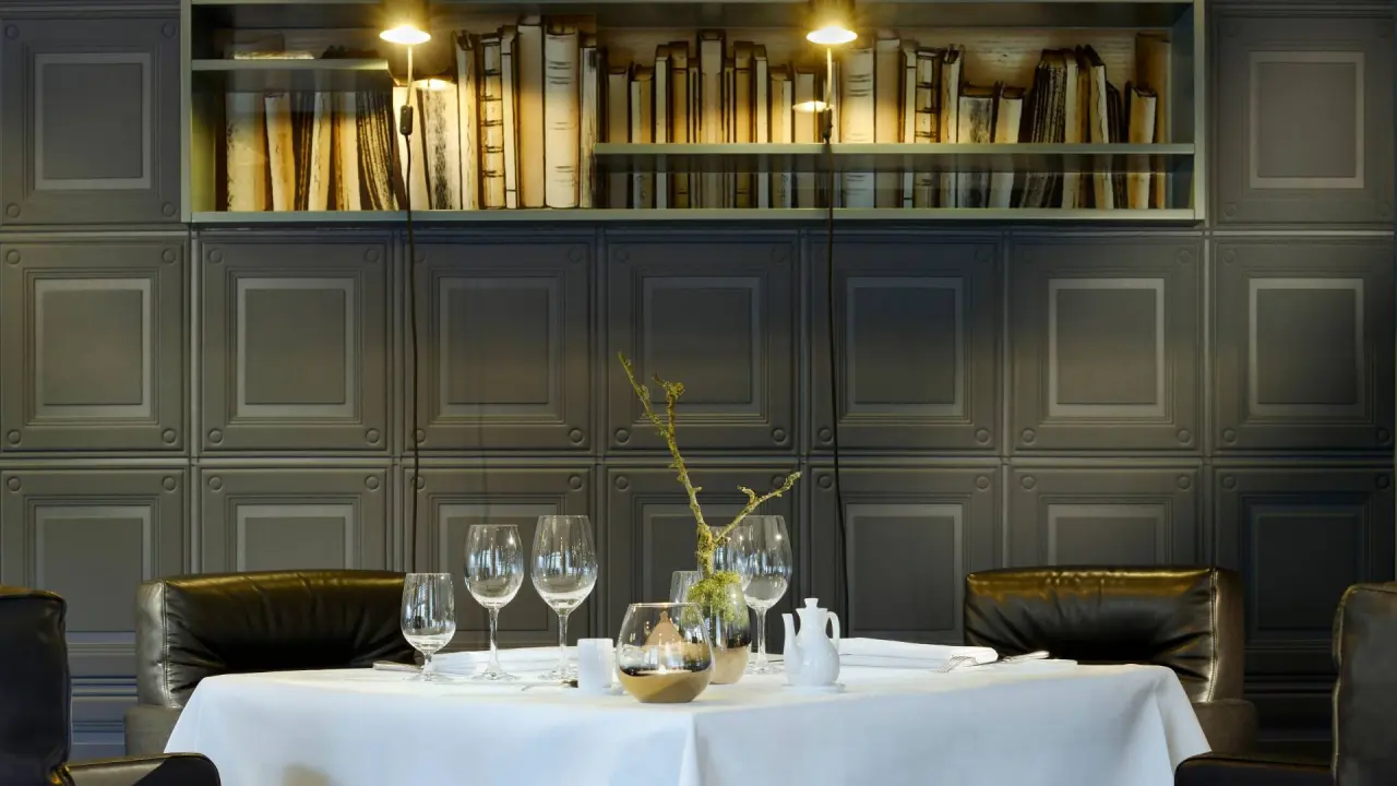 Elegant gedeckter Tisch im Restaurant des Romantik Hotel Jagdhaus Eiden mit stilvoller Wandvertäfelung und Bücherregal.