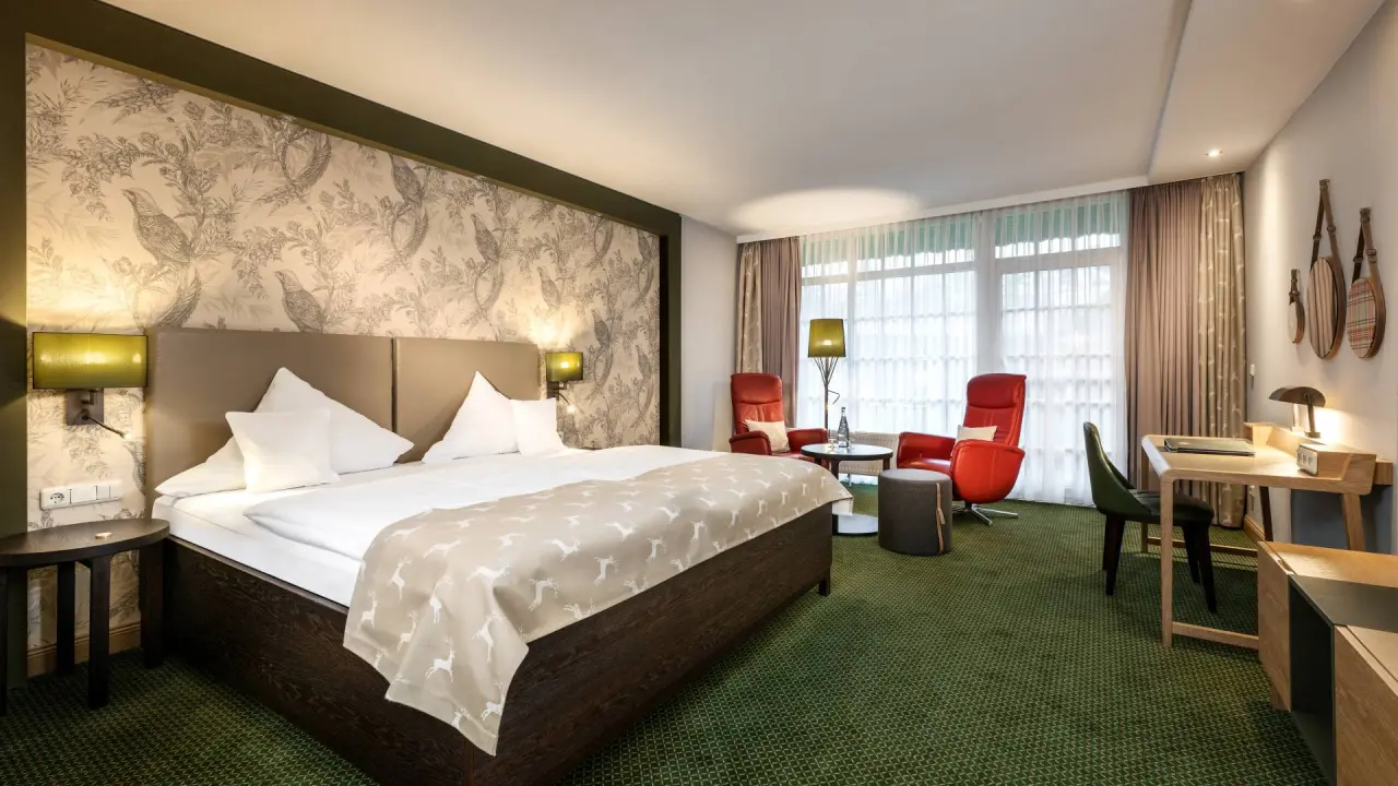 Komfortables Doppelzimmer mit Hirsch-Motiv und gemütlicher Sitzecke im Romantik Hotel Jagdhaus Eiden.