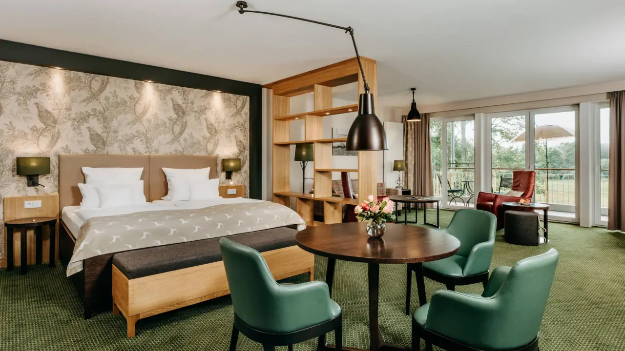Geräumiges Hotelzimmer mit Doppelbett, Sitzbereich und Balkon im Romantik Hotel Jagdhaus Eiden.