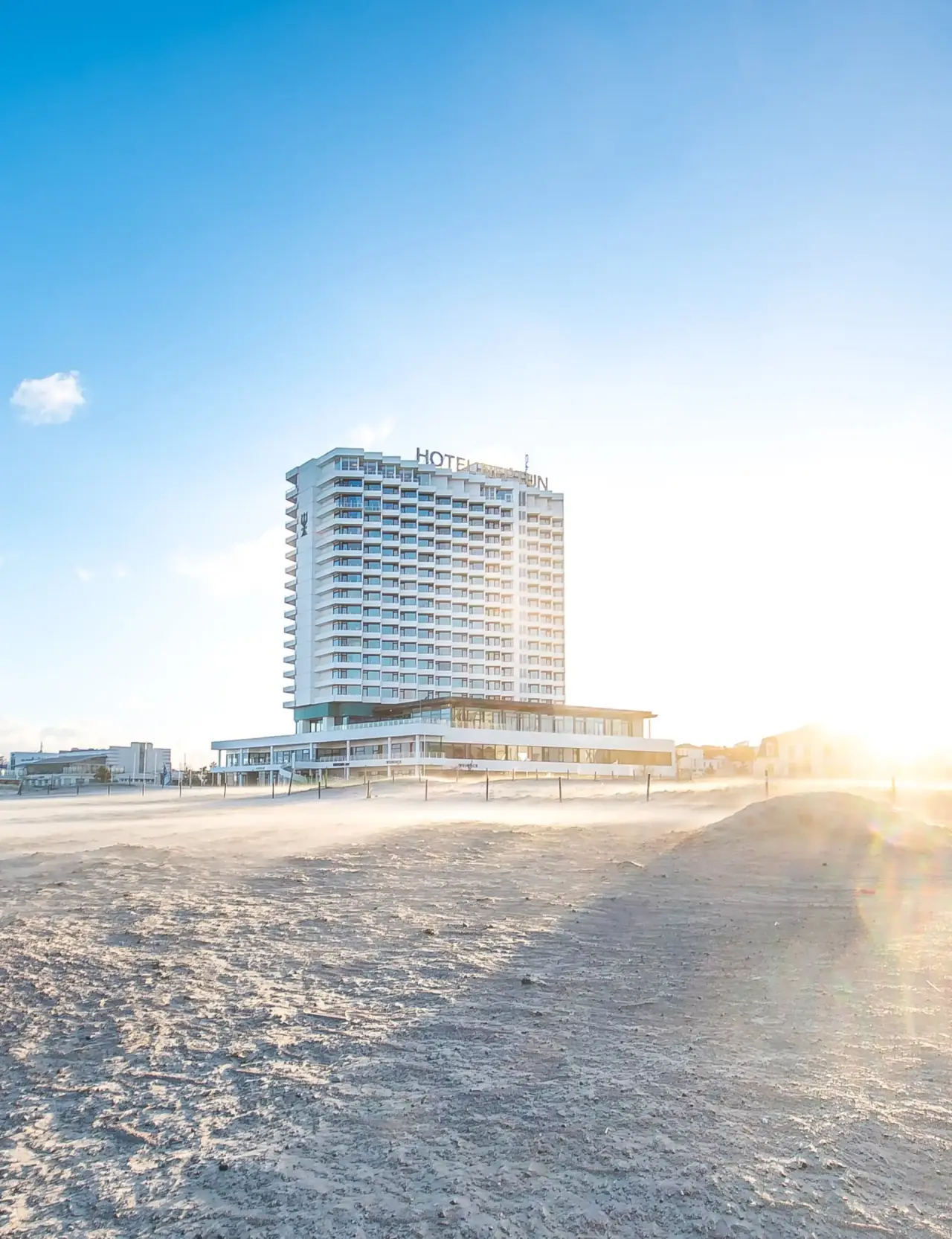 Aussenansicht des Hotel Neptun direkt am Sandstrand unter blauem Himmel. Einladendes Wellnesshotel an der Ostsee.