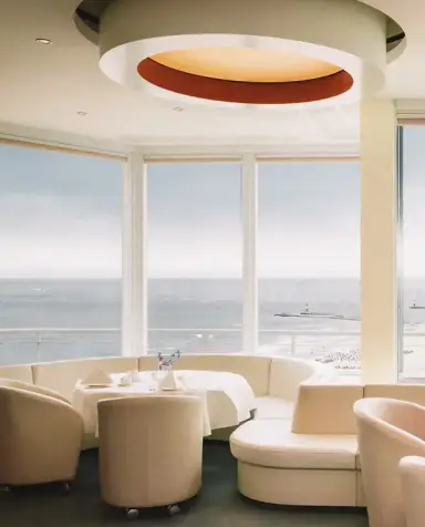 Helles Restaurant im Hotel Neptun mit Meerblick, eleganten Sitzgelegenheiten und Blick auf den Strand und die Ostsee.
