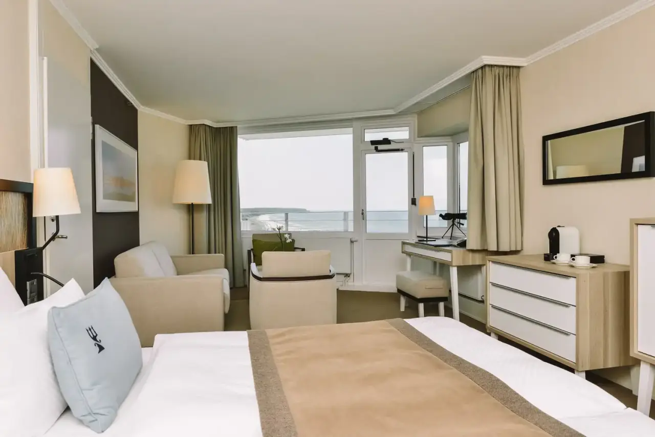 Komfortables Hotelzimmer im Hotel Neptun mit Meerblick, Doppelbett, Sitzgelegenheiten und Zugang zum Balkon.