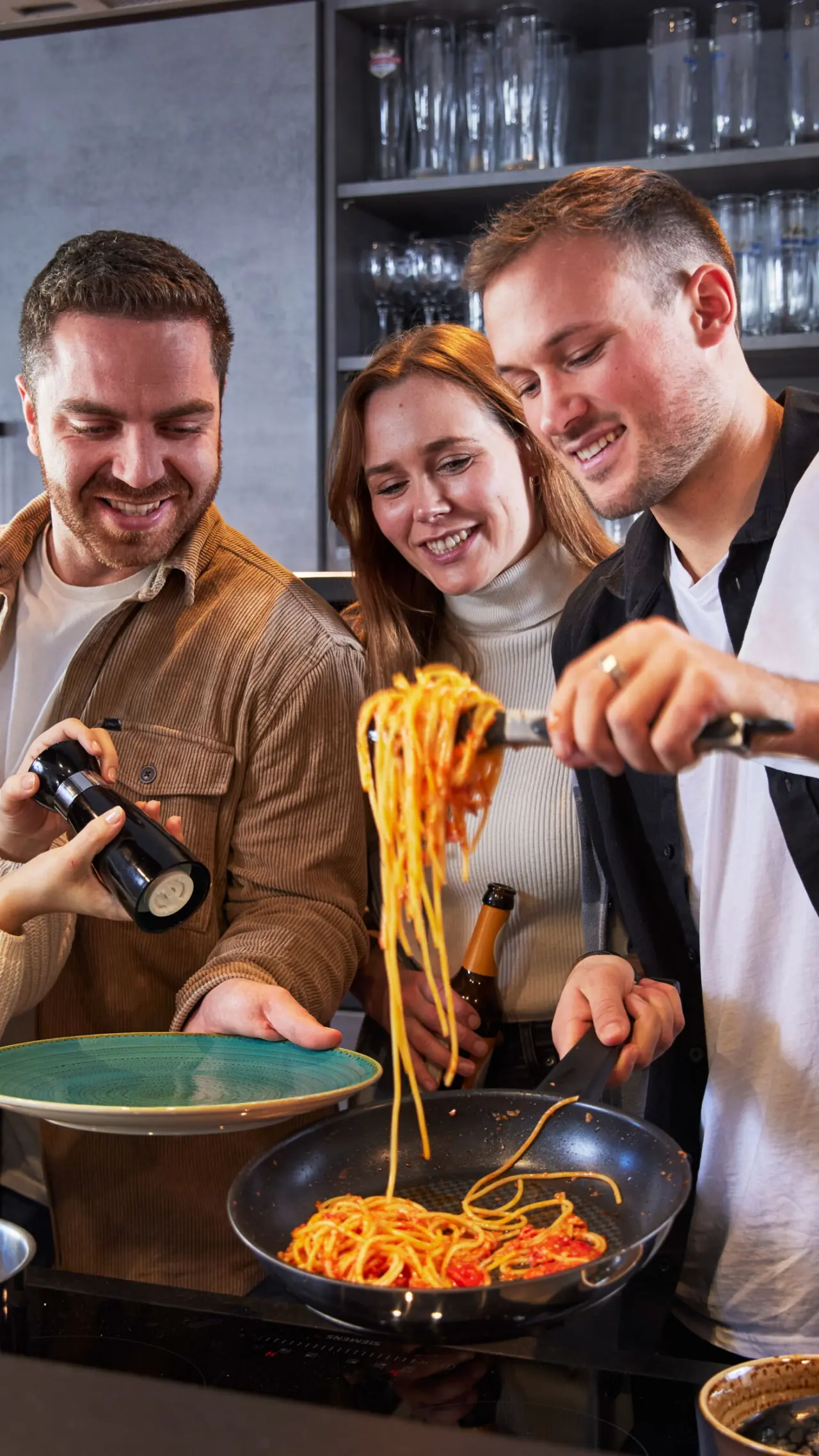 Freunde kochen gemeinsam Pasta in der modernen Küche des Hotel BergBuddies.