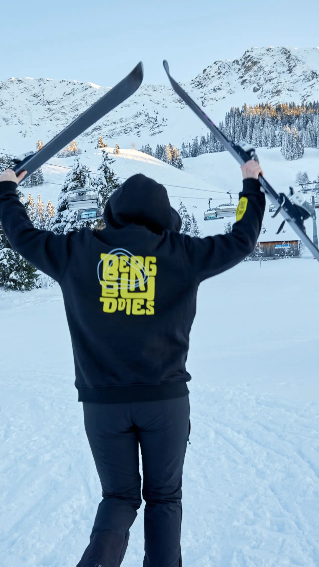 Skifahrer mit Blick auf verschneite Berge und Skilifte im Skigebiet des Hotels BergBuddies.