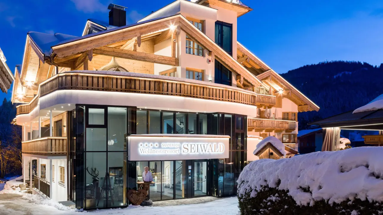 Beleuchtetes Wellnessresort Seiwald im Winter bei Nacht, mit Schnee und traditioneller alpiner Architektur.