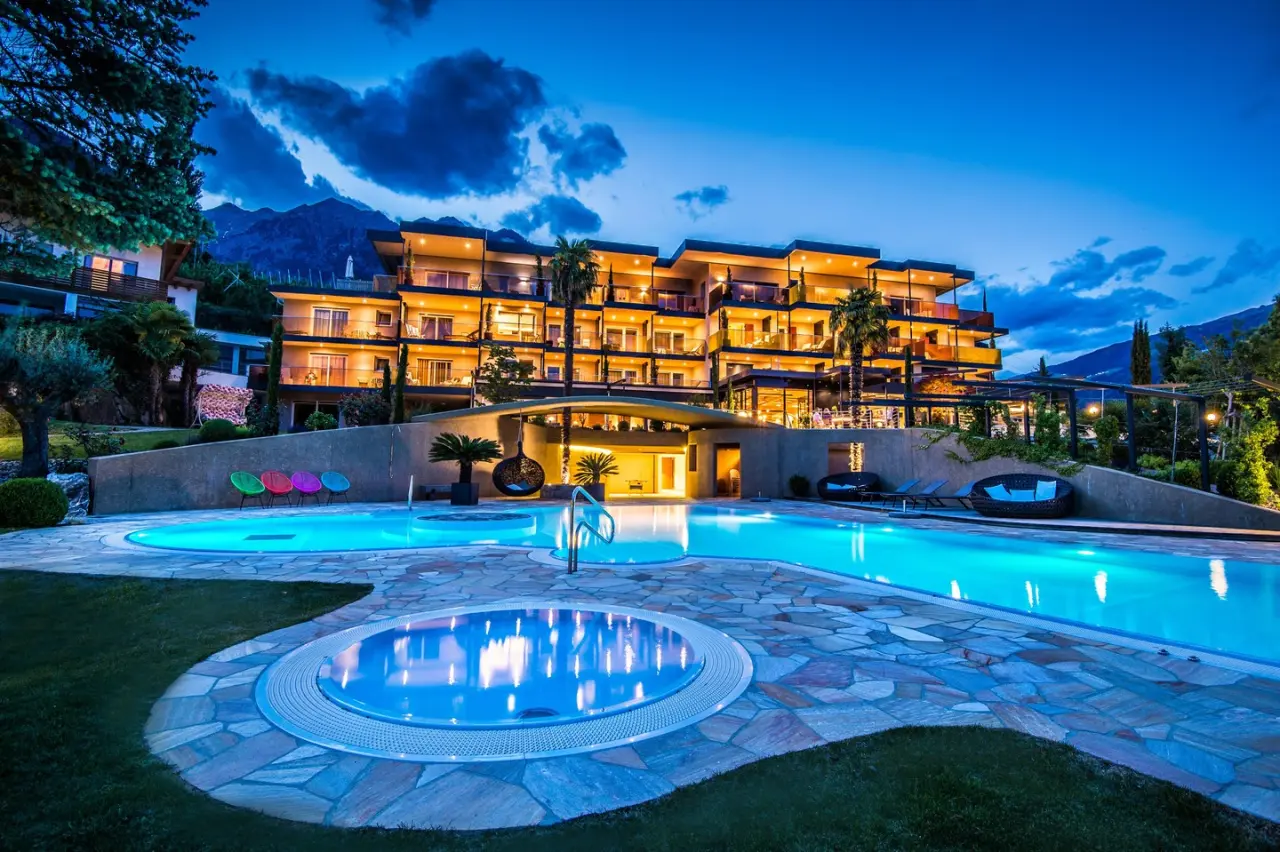 Feel Good Resort Johannis in Dorf Tirol – Beleuchteter Außenpool und Hotelgebäude am Abend | Wellnesshotel Südtirol