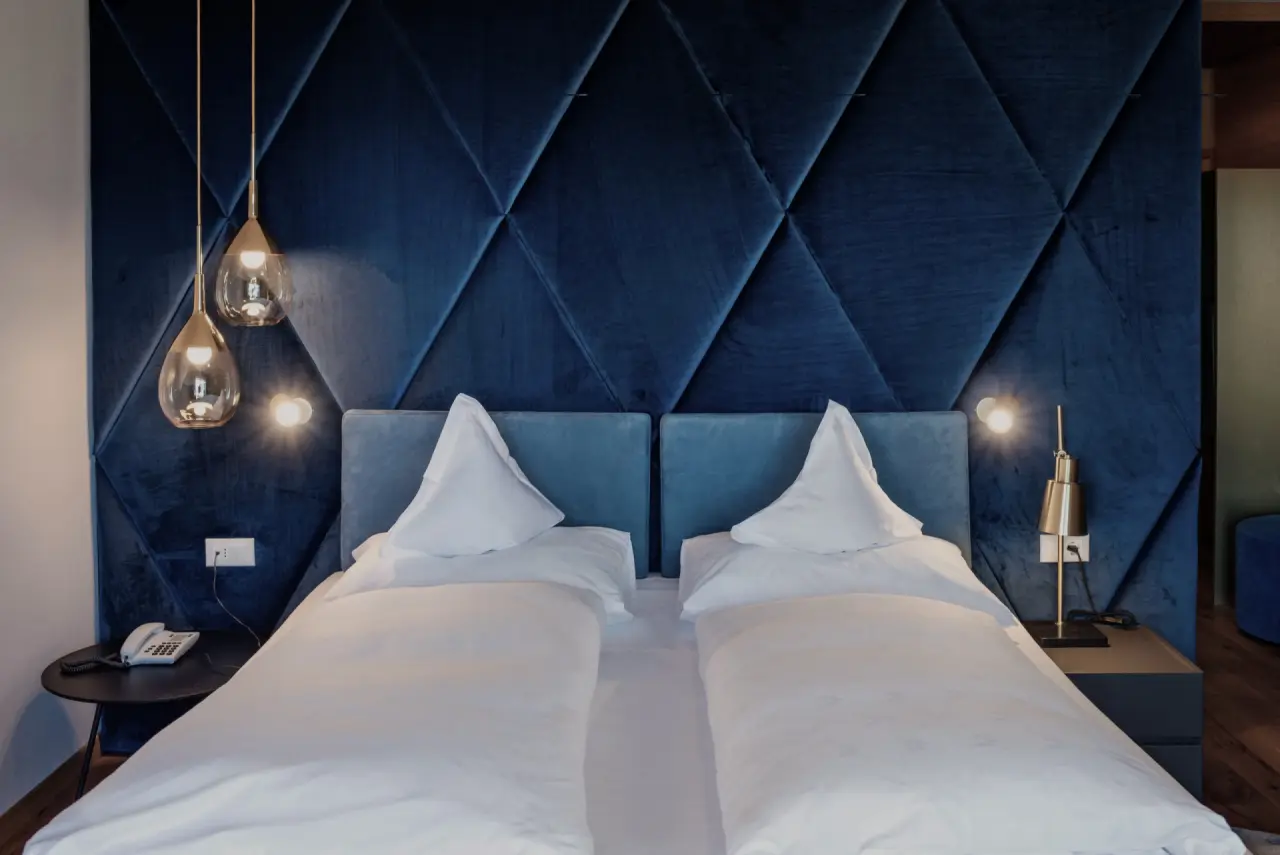Feel Good Resort Johannis in Dorf Tirol – Modernes Doppelbett mit blauer Samtwand | Wellnesshotel Südtirol