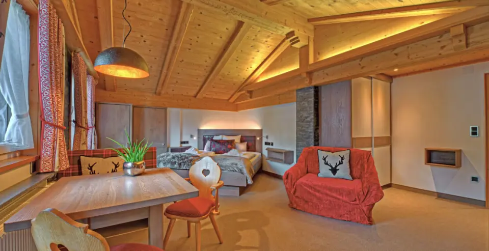 Gemütliches Hotelzimmer im alpinen Stil mit Holzbalkendecke, Doppelbett und Sitzecke im DIANA Naturpark Hotel.