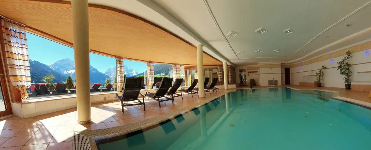 Grosszügiger Innenpool mit Liegebereich und Panoramablick auf die verschneiten Berge im Hotel Birkenhöhe.