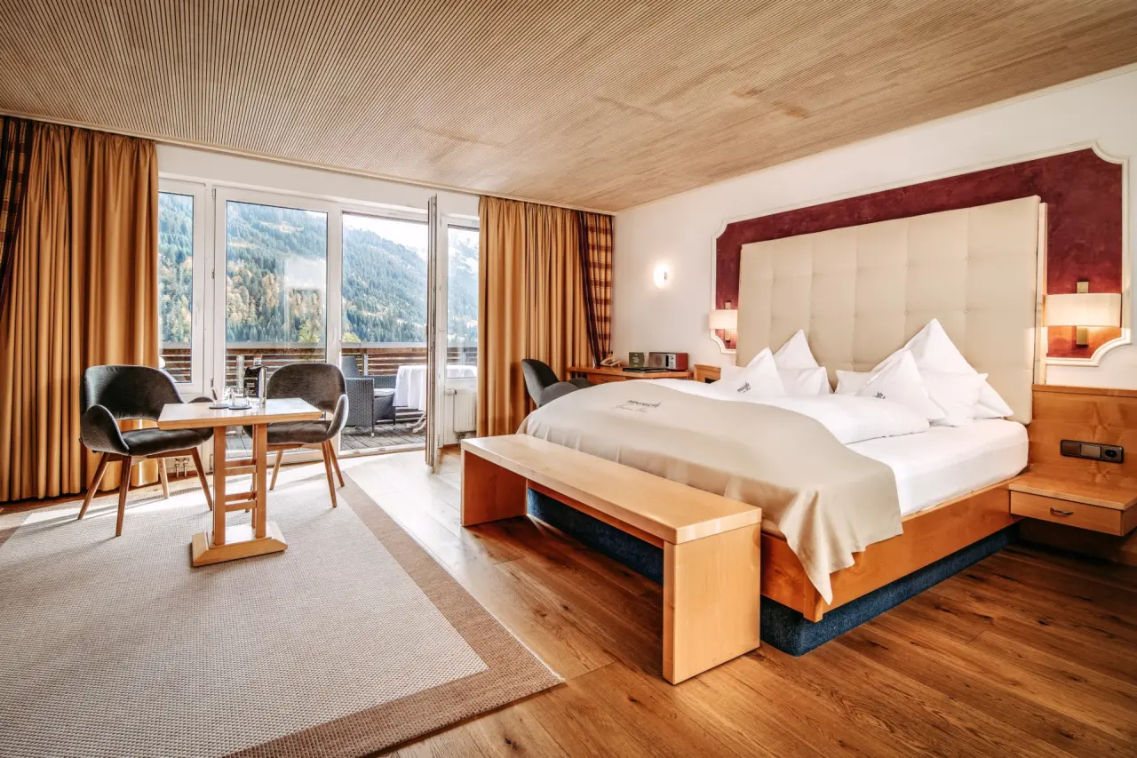 Komfortables Hotelzimmer im Hotel Birkenhöhe mit Doppelbett, Holzboden und Balkon mit malerischem Bergblick.