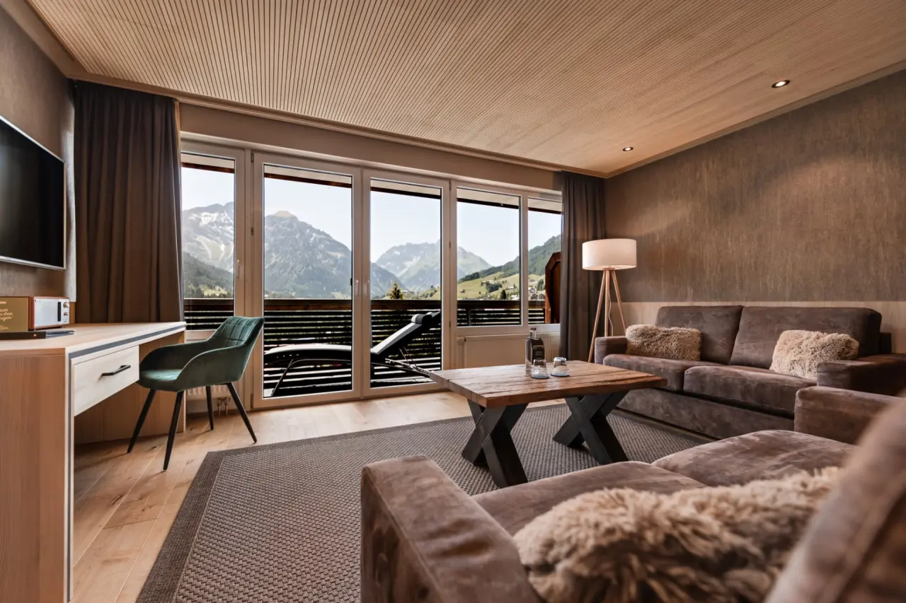 Gemütliches Hotelzimmer im Hotel Birkenhöhe mit Wohnbereich, Schreibtisch und Balkon mit atemberaubendem Bergblick.