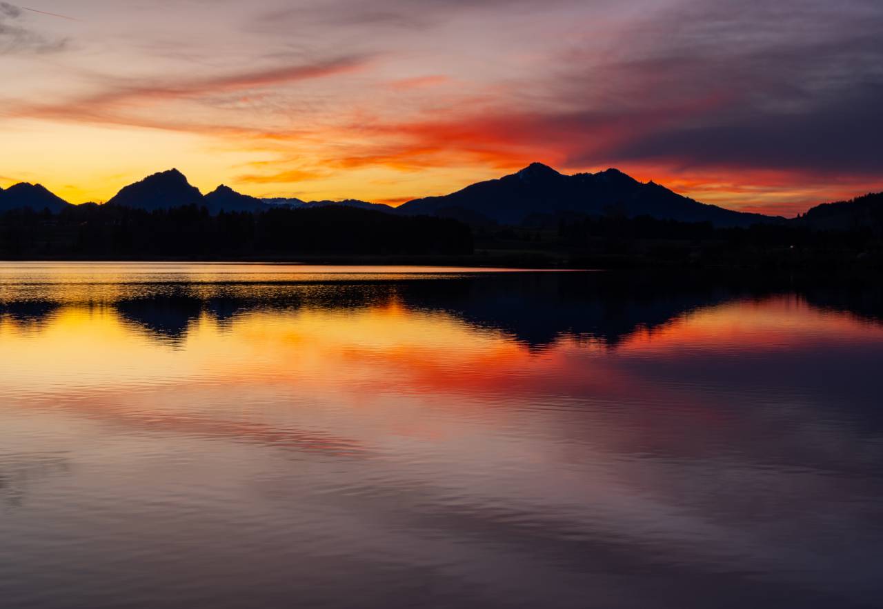 Hartung’s Hoteldorf in Füssen – Sonnenuntergang über See mit Bergpanorama | Wellnesshotel Allgäu