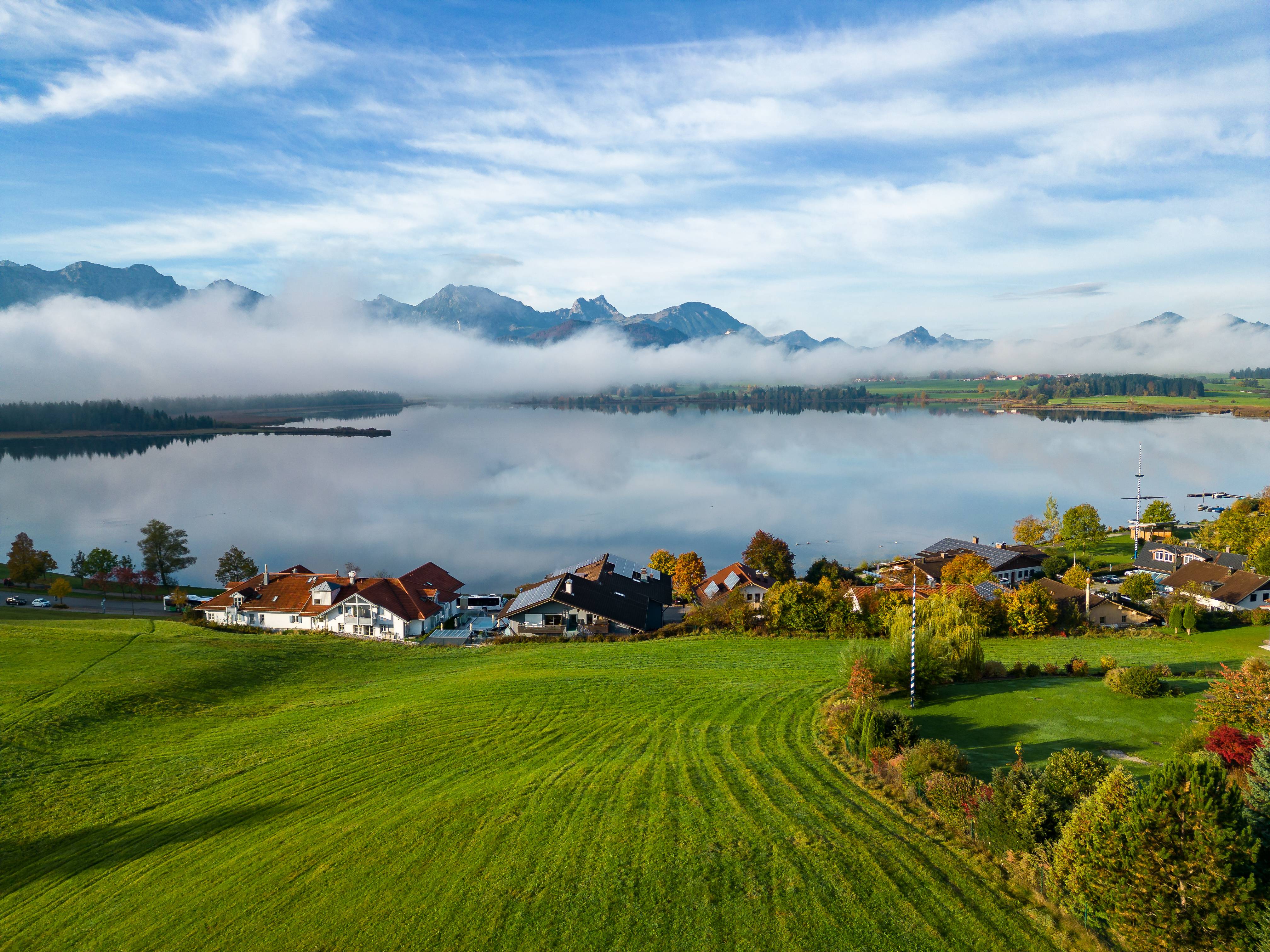 Hartung’s Hoteldorf in Füssen – Herbstliches Dorf am See mit Nebel über den Bergen | Wellnesshotel Allgäu