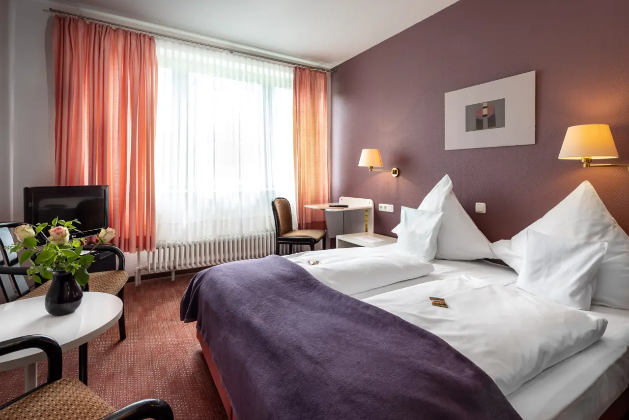 Gemütliches Doppelzimmer im Parkhotel Hitzacker mit bequemen Betten, Sitzbereich und Tageslicht.