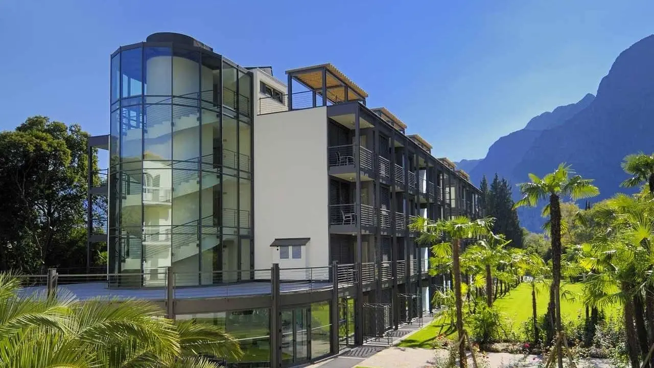 Du Lac et Du Parc Grand Resort in Riva del Garda – Moderne Hotelfassade mit Palmen und Bergkulisse | Wellnesshotel Gardasee