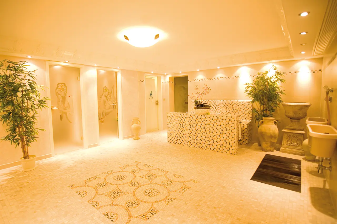 Heller Spa-Eingangsbereich im ANGERHOF Kur- und Sporthotel mit Mosaikfliesen, Pflanzen und Zugang zu Behandlungsräumen.