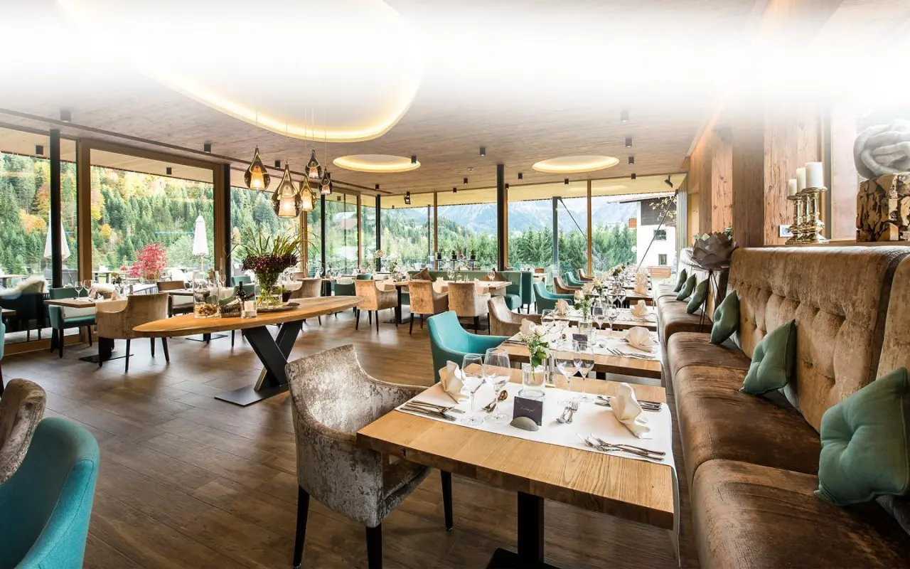 Elegantes Restaurant im Wellnesshotel Walserhof mit Bergblick, Holzelementen und stilvoller Einrichtung.