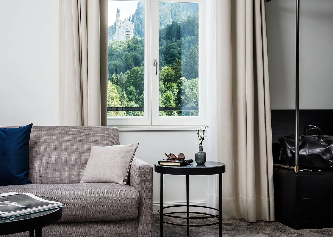 AMERON Neuschwanstein Alpsee Resort & Spa in Hohenschwangau – Gemütlicher Wohnbereich mit Blick auf Schloss Neuschwanstein | Wellnesshotel Allgäu