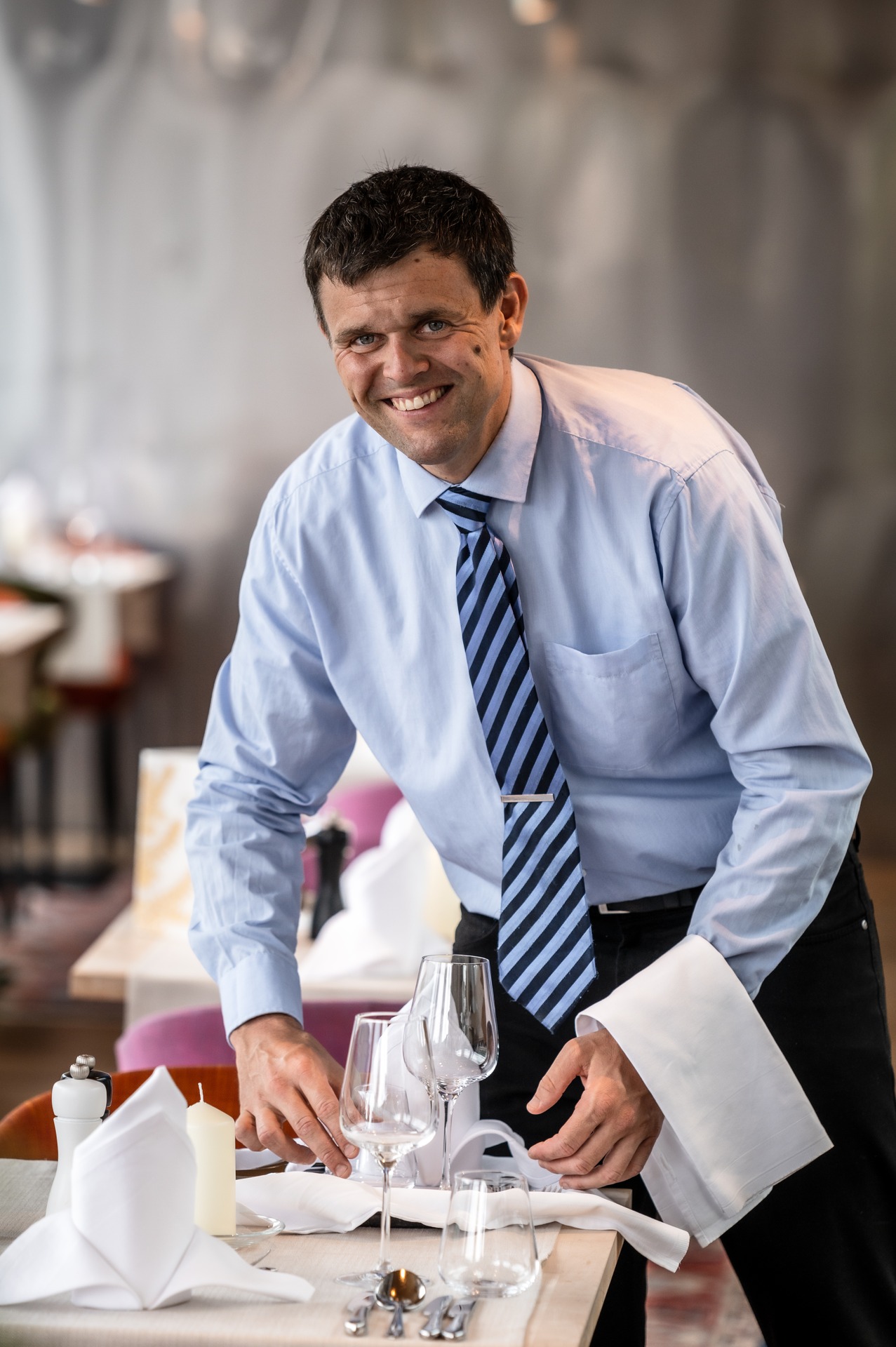 Gardenhotel Crystal in Fügen – Freundlicher Mitarbeiter deckt Tisch im Restaurant | Wellnesshotel Zillertal
