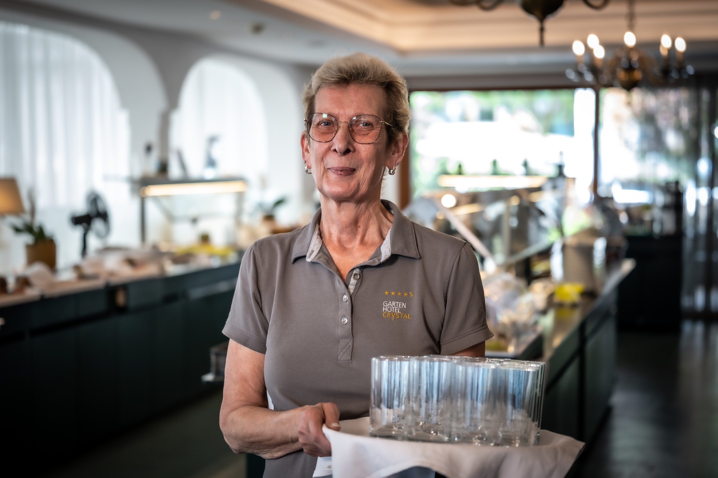 Gardenhotel Crystal in Fügen – Mitarbeiterin mit Tablett im Buffetbereich des Hotels | Wellnesshotel Zillertal