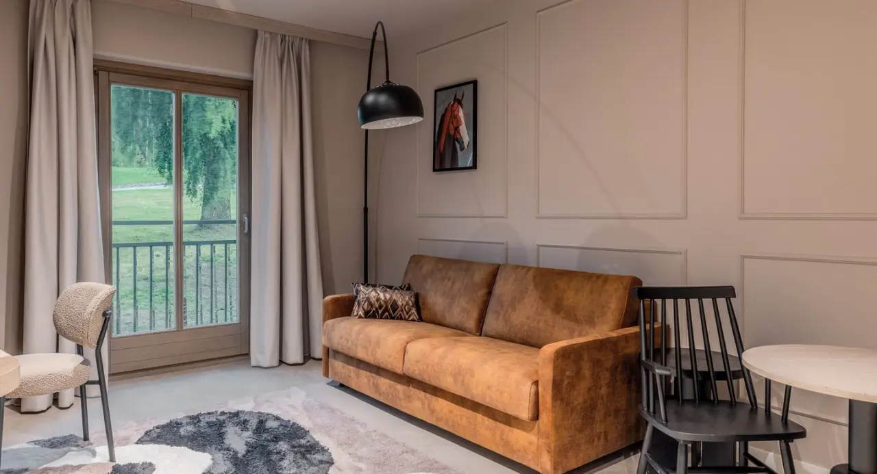 Gemütliches Hotelzimmer im Aldiana Club Ampflwang mit Sofa, Sesseln und Blick ins Grüne.