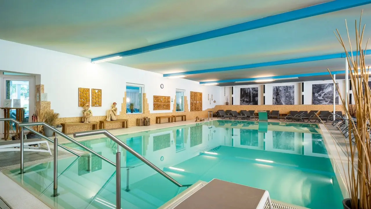 Grosszügiger Innenpool im Wellnessbereich des Waldhotel Tannenhäuschen mit hellen Farben und Entspannungsbereich.