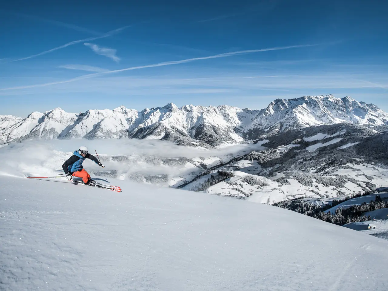 Dynamischer Skifahrer auf sonniger Piste mit majestätischem Alpenpanorama. Idealer Winterurlaub im Hotel Mitterwirt.