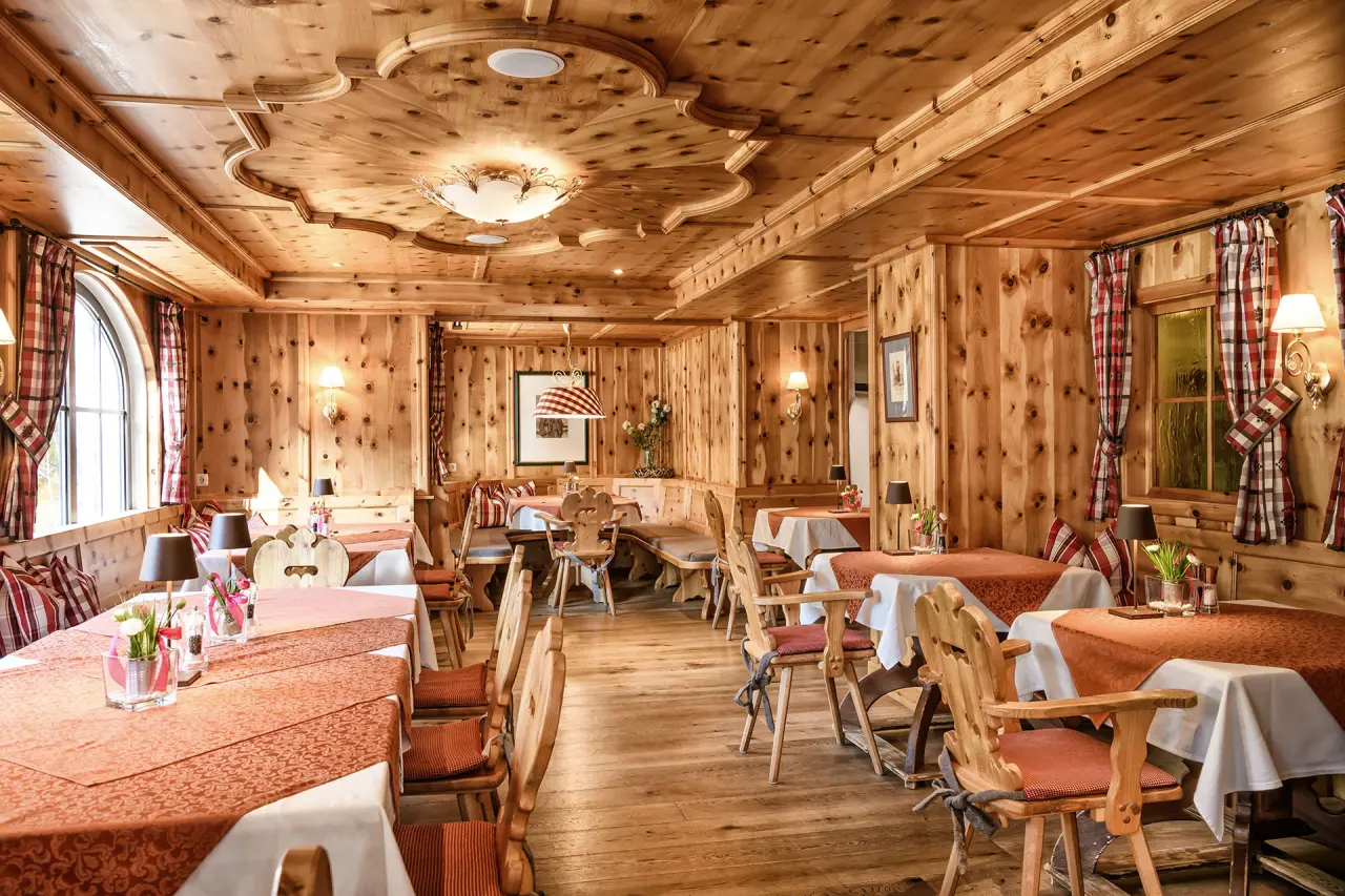 Gemütliches Restaurant im alpenländischen Stil mit Holztäfelung und festlich gedeckten Tischen im Hotel Mitterwirt.