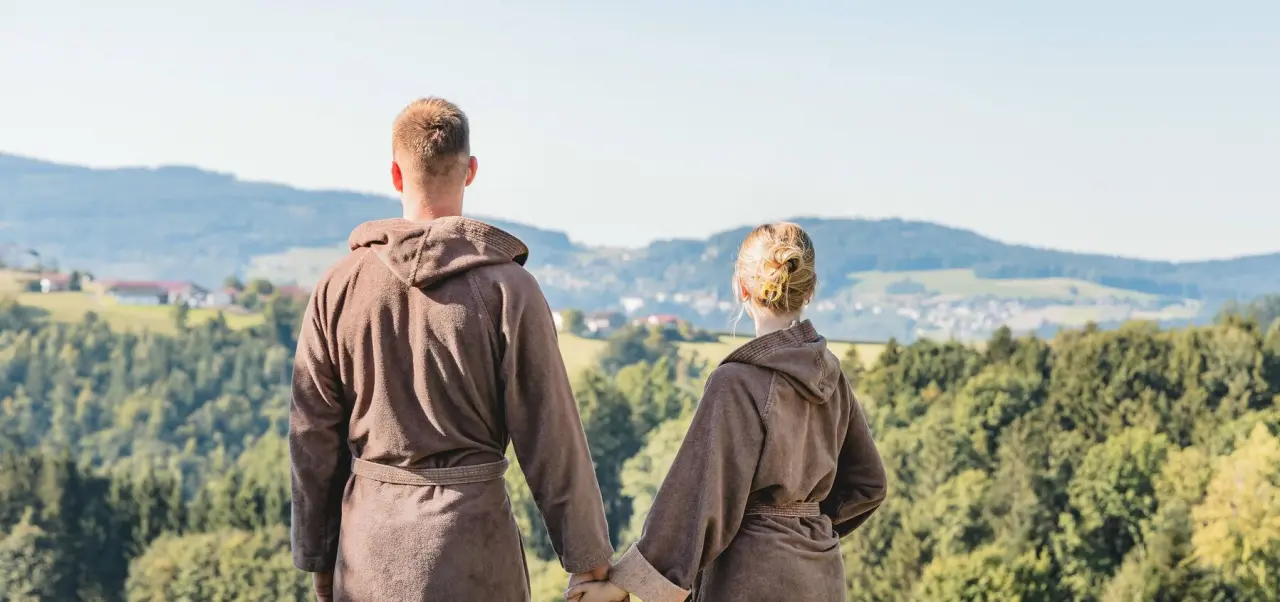 Paar in Bademänteln genießt den Panoramablick über die Naturlandschaft des Landrefugium Obermüller.