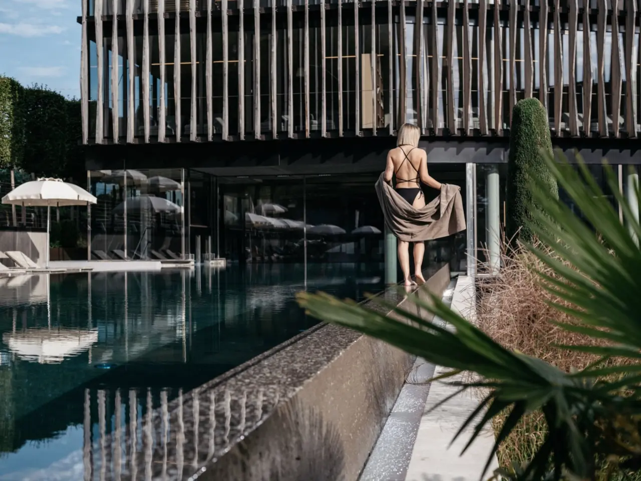 Lindenhof Pure Luxury & Spa in Naturns – Frau am Infinity-Pool vor moderner Hotelfassade | Wellnesshotel Südtirol