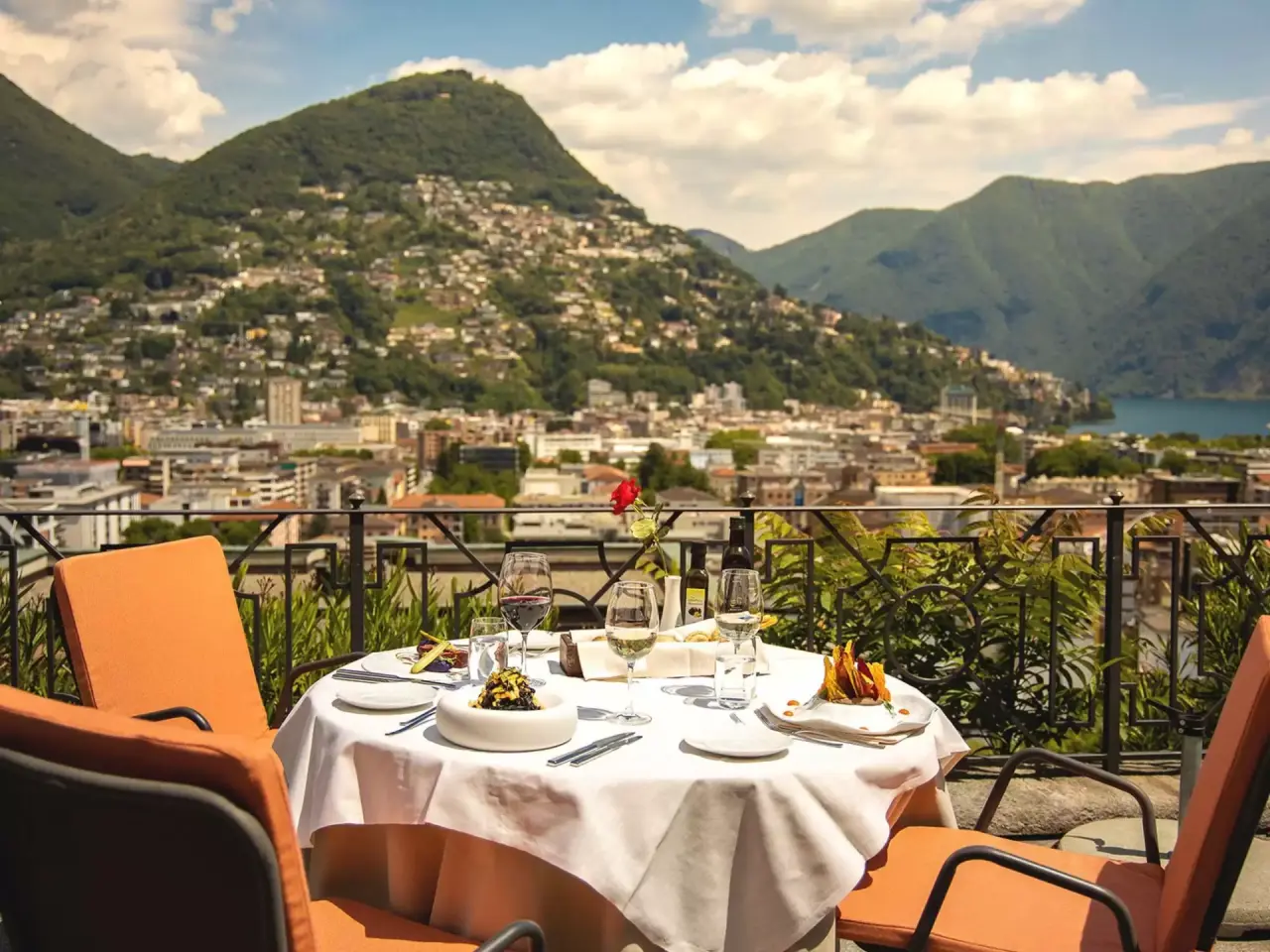 Elegante Restaurantterrasse der Villa Sassa mit gedecktem Tisch und Panoramablick auf Lugano, Berge und den Luganersee.