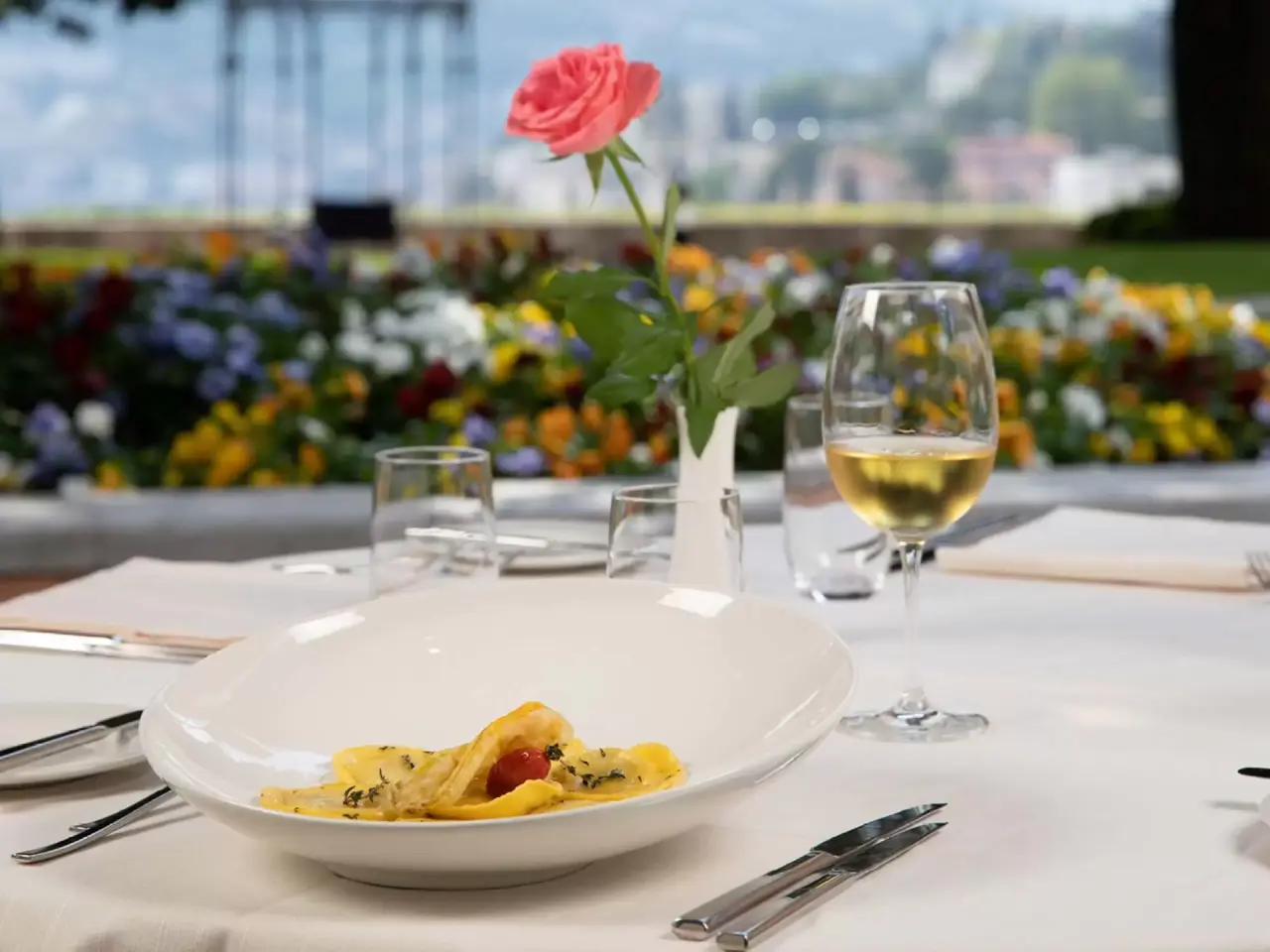 Fein gedeckter Tisch mit Pasta, Weisswein und Rose auf der Terrasse des Villa Sassa Hotel Residence & SPA.