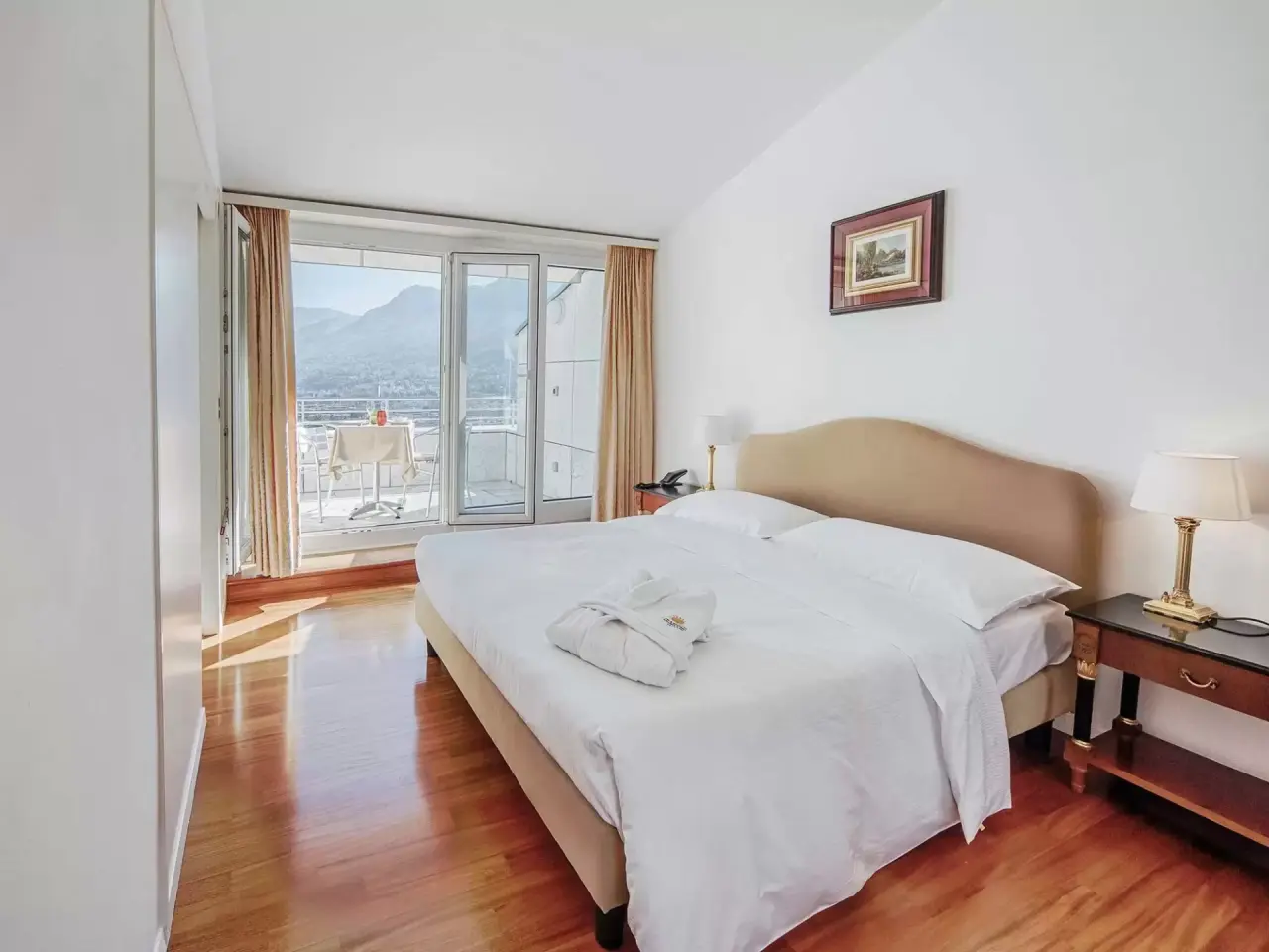 Geräumiges Hotelzimmer mit Doppelbett, Bademantel und Balkon mit Bergblick im Villa Sassa Hotel Residence & SPA.