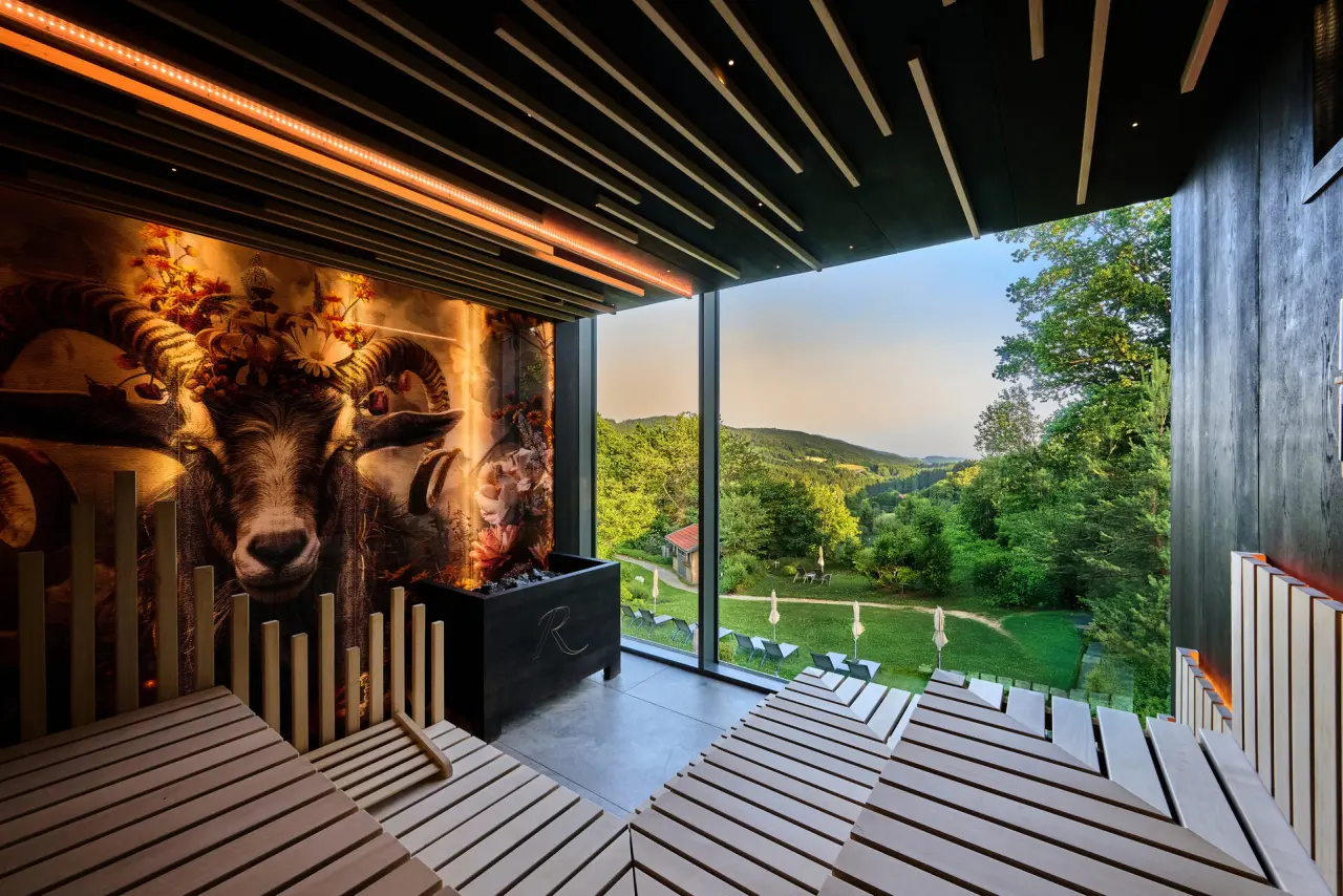 Moderne Panoramasauna mit Blick ins Grüne und künstlerischer Wandgestaltung im Hotel Reinerhof