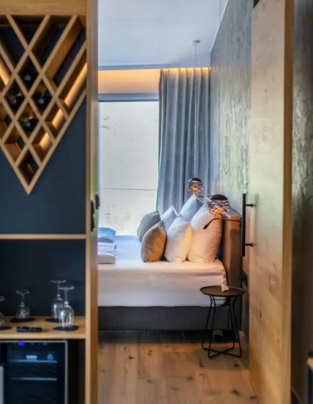 Modernes Doppelzimmer mit Holzboden, gemütlichem Bett und integriertem Weinregal im Moselromantik Hotel Keßler-Meyer.