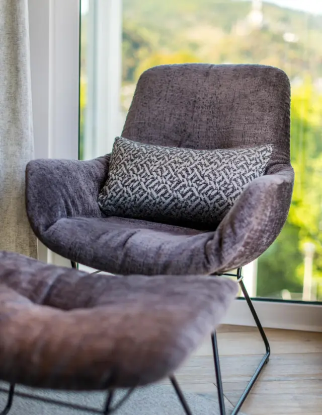Gemütlicher Sessel mit Fußhocker und Blick ins Grüne im Moselromantik Hotel Keßler-Meyer.