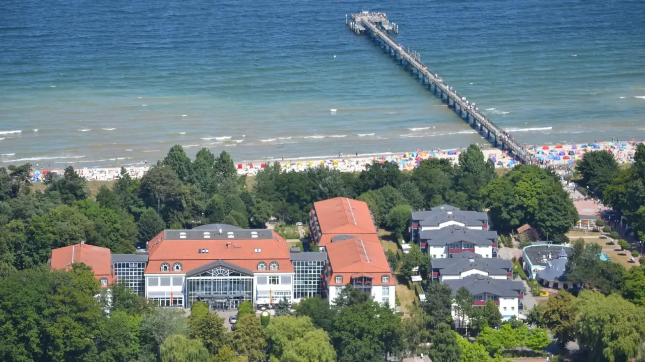Luftaufnahme des Seehotel Grossherzog v. Mecklenburg mit Strand, Ostsee und Seebr\u00fccke bei strahlendem Sonnenschein.