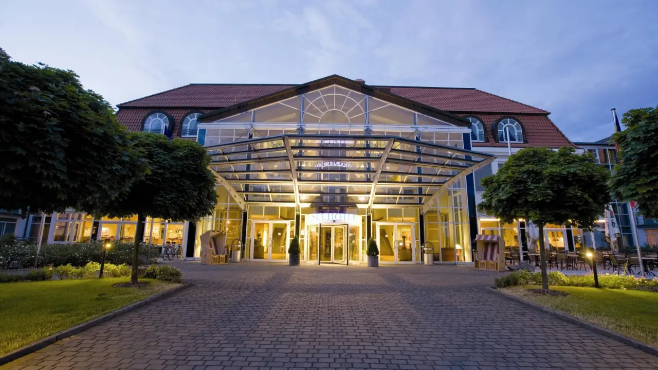 Beleuchteter Eingangsbereich des Seehotel Grossherzog v. Mecklenburg bei Abenddämmerung. Einladende Hotelansicht.