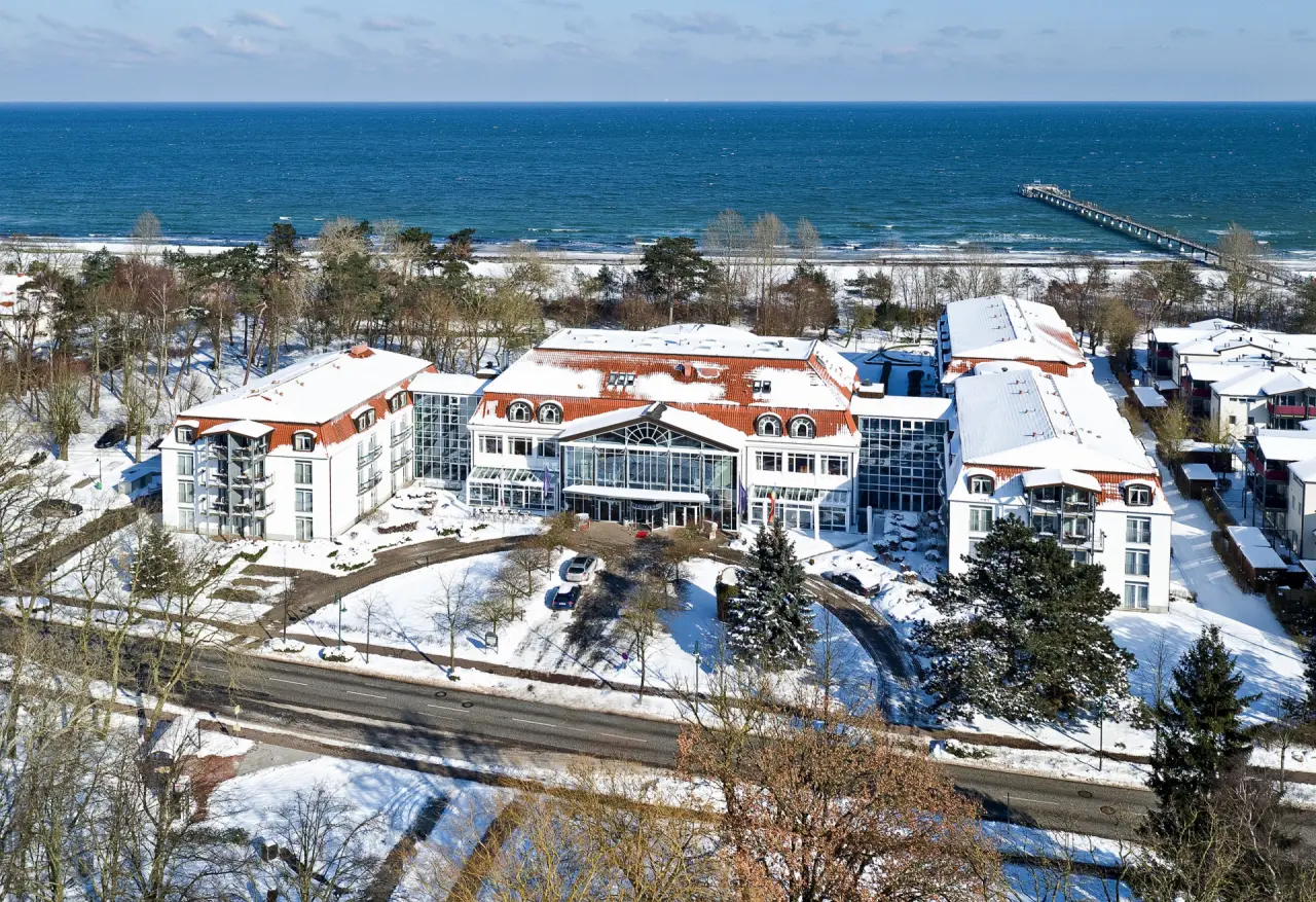 Luftaufnahme des Seehotel Grossherzog v. Mecklenburg im Winter mit schneebedeckten Dächern und Ostseeblick.