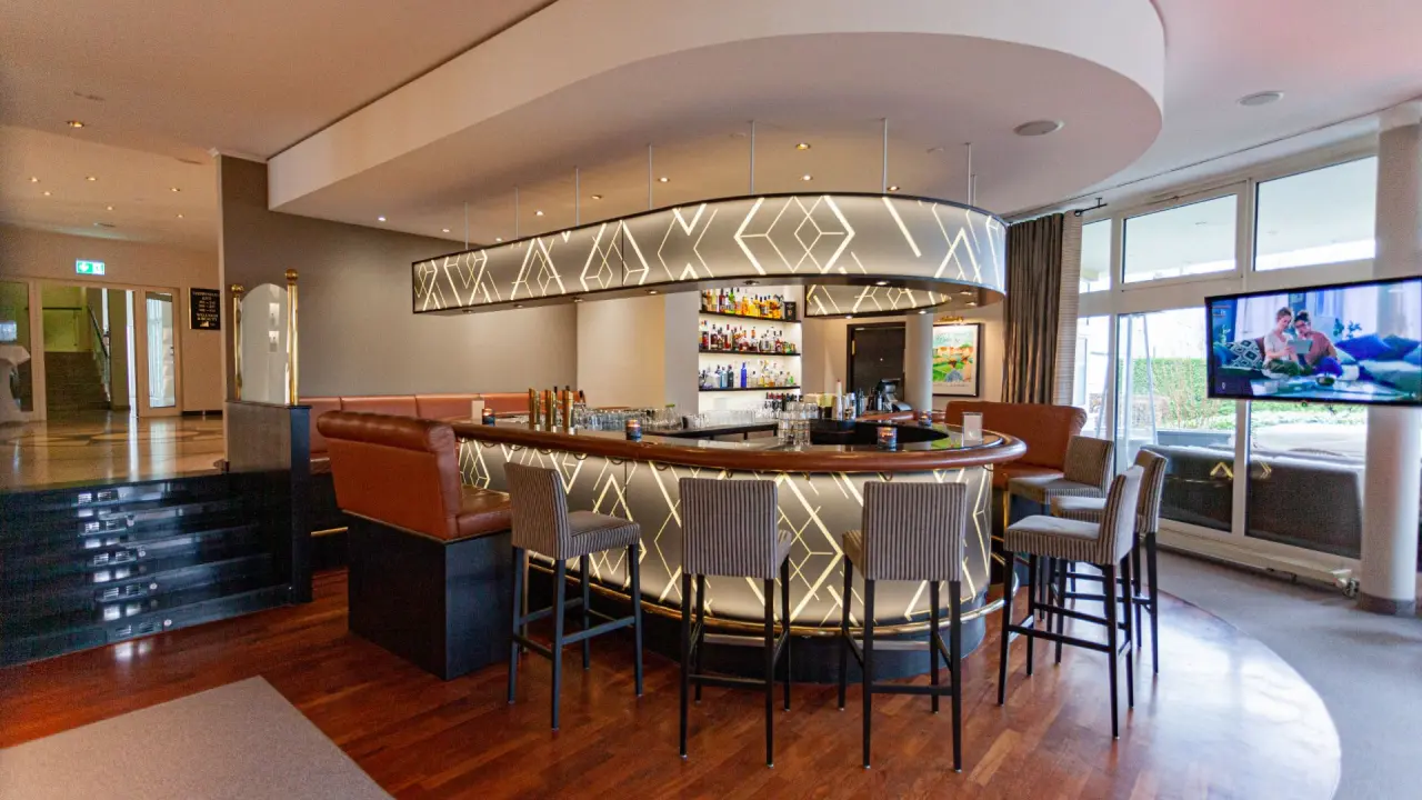 Moderne, beleuchtete Hotelbar mit stilvollen Sitzgelegenheiten im COURT HOTEL. Einladender Bereich für entspannte Abende.