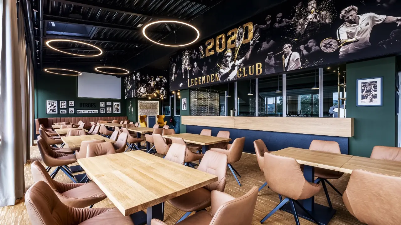 Modernes Restaurant 'Legenden Club' im COURT HOTEL mit Tischen, Ledersesseln und Wandgemälde von Sportlegenden.