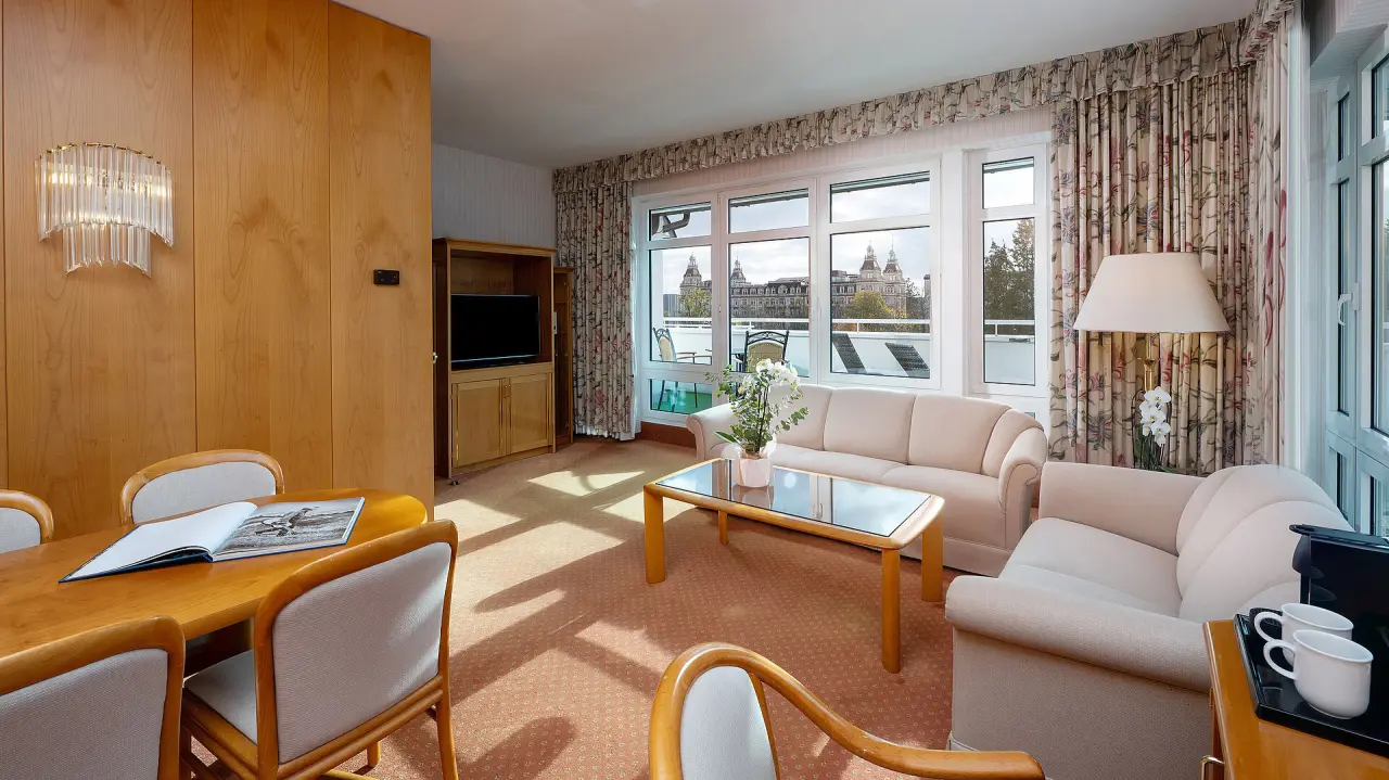 Geräumige Suite im Maritim Hotel Bad Wildungen mit Wohnbereich, Esstisch und Blick auf das historische Kurhaus.