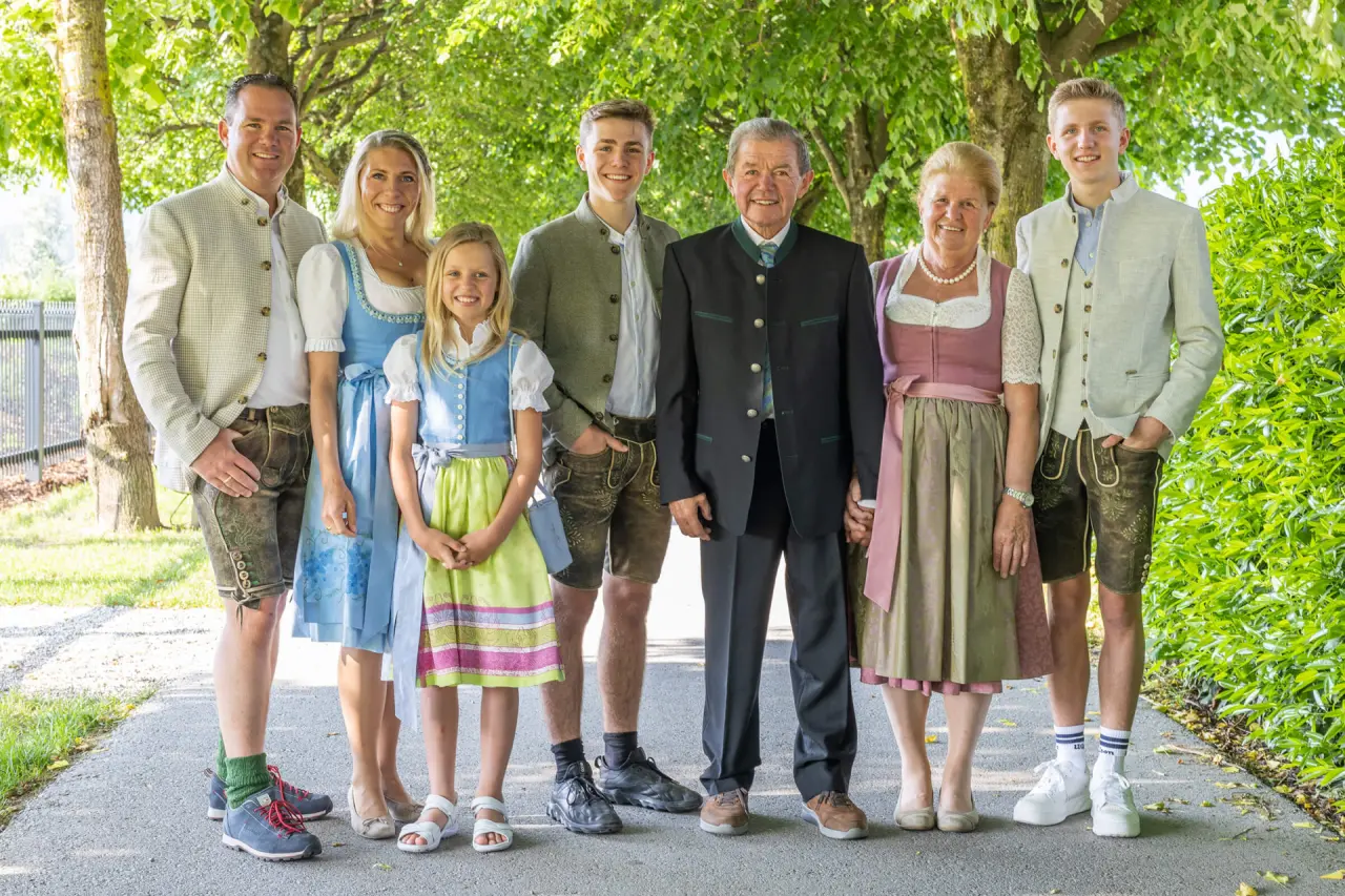Familie Laschenskyhof in traditioneller Tracht vor grüner Baumkulisse, die Gastgeber des Hotels Laschenskyhof.