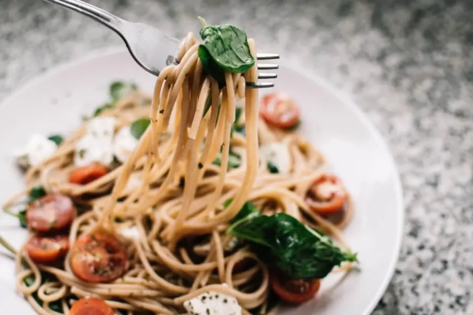 Frische Vollkorn-Spaghetti mit Kirschtomaten, Mozzarella und Basilikum auf einer Gabel im Restaurant des Laschenskyhofs.