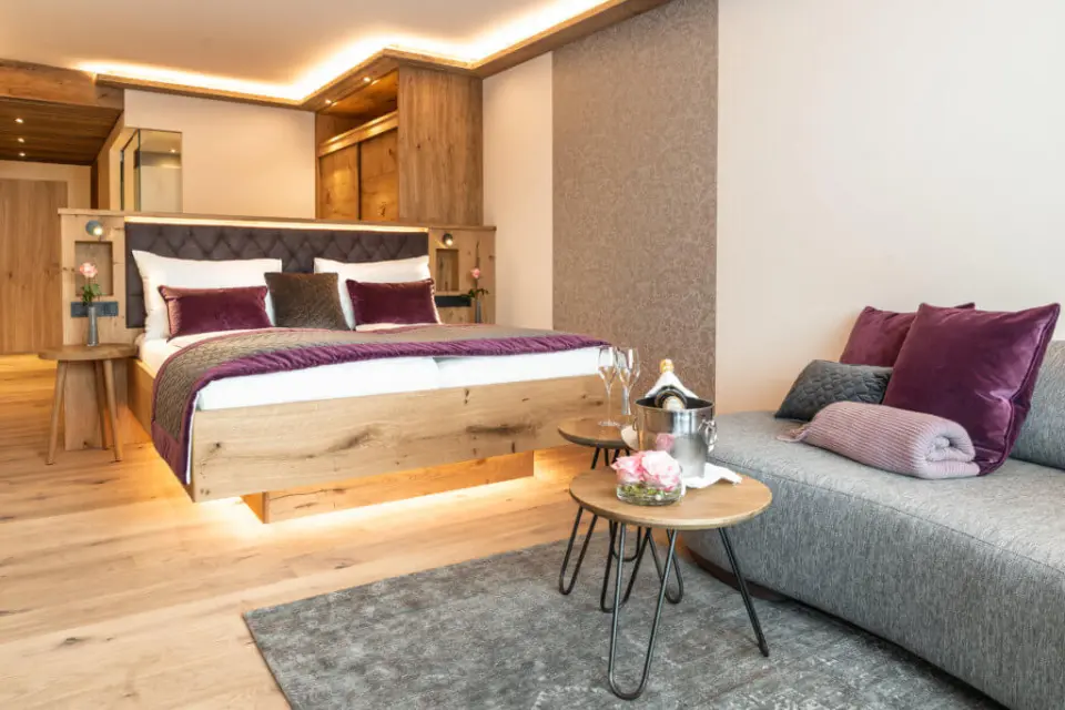 Stilvolles Doppelzimmer mit Holzelementen, gemütlichem Bett und Sitzbereich mit Champagner im Hotel Laschenskyhof.