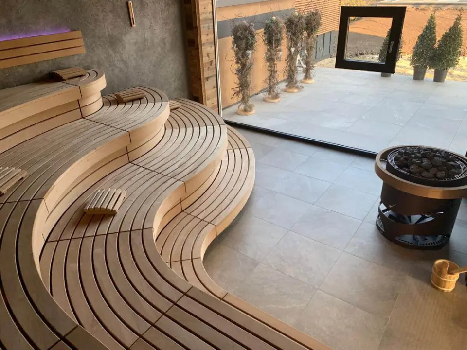 Moderne Finnische Sauna mit geschwungenen Holzbänken und Blick ins Grüne im Wellnessbereich des Hotel Laschenskyhof.