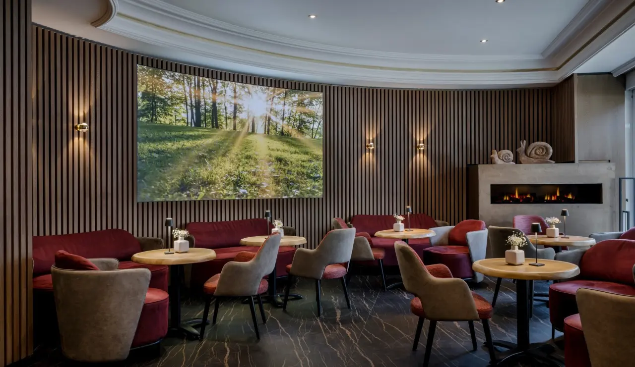 Einladende Hotellounge im Hotel Lamm mit bequemen Sesseln, Kamin und grosser Naturprojektion für entspannte Momente.