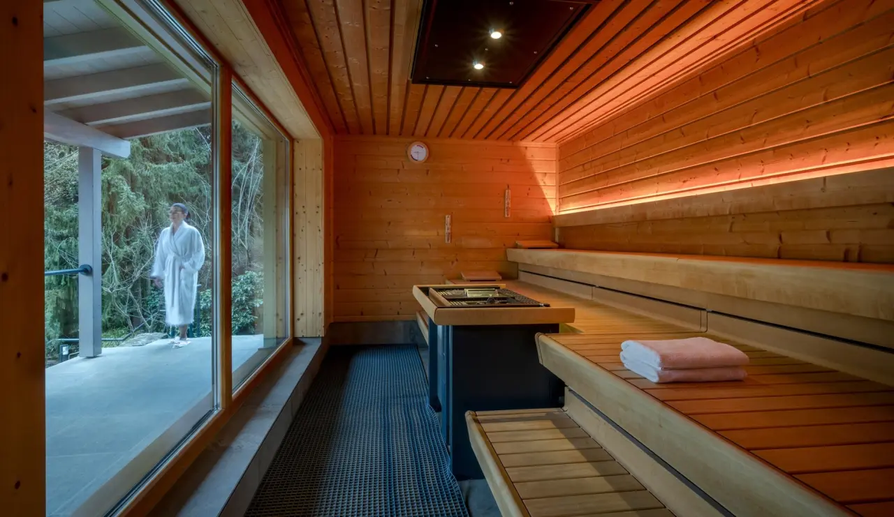 Moderne Holzsauna mit Panoramablick in die Natur und Gast im Bademantel im Hotel Lamm.
