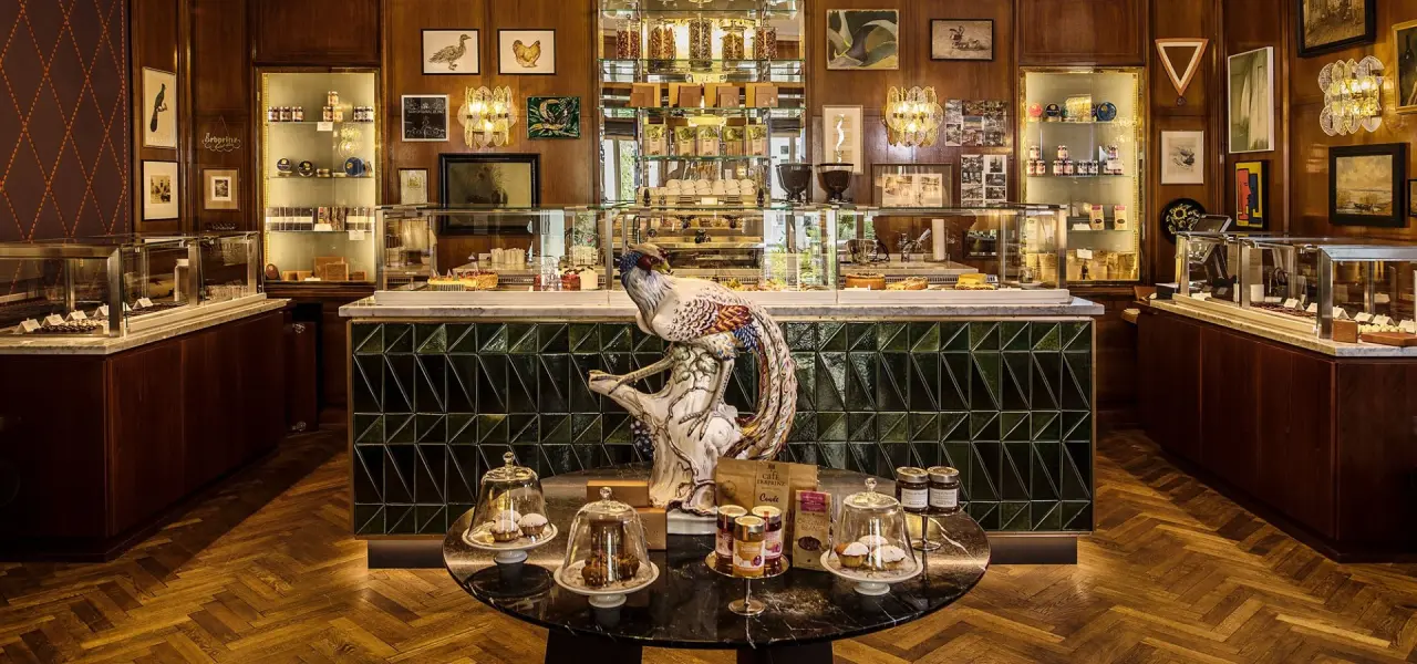 Elegante Patisserie mit Kuchen und Feinkost im Hotel Erbprinz. Luxuriöser Ladenbereich mit Holzvertäfelung und Vitrinen.