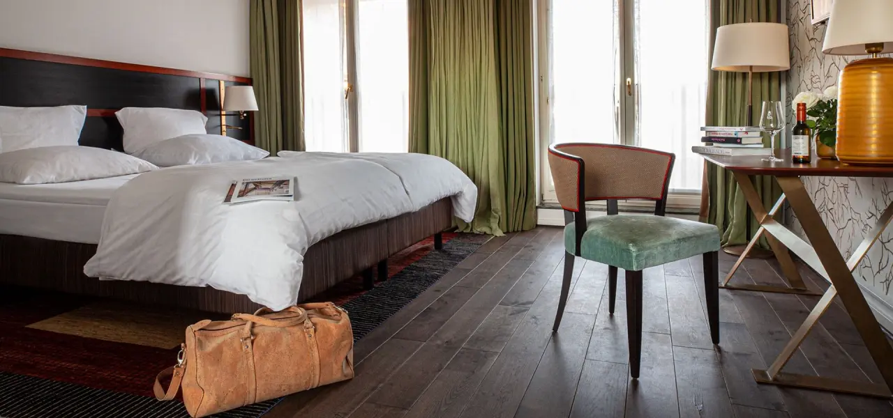 Komfortables Hotelzimmer im Hotel Erbprinz mit Doppelbett, elegantem Sessel und Schreibtisch mit Willkommensgruß.